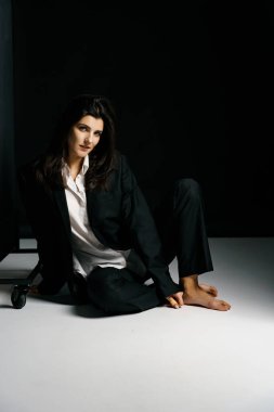 Profesyonel bir fotoğraf stüdyosunda siyah takım elbise ve beyaz gömlek içinde şık bir kız. Moda çekim konsepti