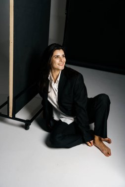 Profesyonel bir fotoğraf stüdyosunda siyah takım elbise ve beyaz gömlek içinde şık bir kız. Moda çekim konsepti