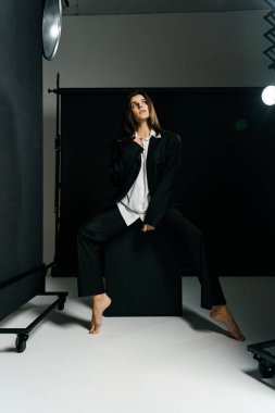 Profesyonel bir fotoğraf stüdyosunda siyah takım elbise ve beyaz gömlek içinde şık bir kız. Moda çekim konsepti