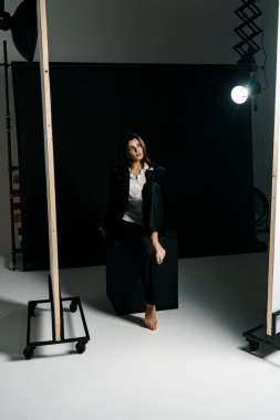 Profesyonel bir fotoğraf stüdyosunda siyah takım elbise ve beyaz gömlek içinde şık bir kız. Moda çekim konsepti