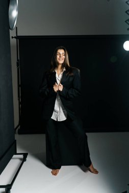 Profesyonel bir fotoğraf stüdyosunda siyah takım elbise ve beyaz gömlek içinde şık bir kız. Moda çekim konsepti