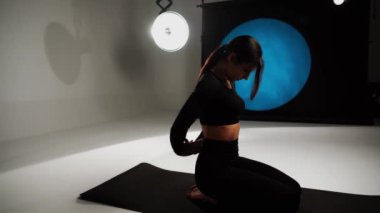 Atletik kadın fotoğraf stüdyosunda yoga yapıyor. Yoga ve meditasyon konsepti. 4k