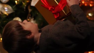 Mutlu aile babası, anne ve oğlu yeni yıl ağacını süslüyor, eğleniyor, dans ediyor ve hediyeleri açıyor. Noel ve Yeni Yıl Arifesi kavramı. Dikey video