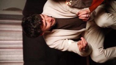 Mutlu aile babası, anne ve oğlu yeni yıl ağacını süslüyor, eğleniyor, dans ediyor ve hediyeleri açıyor. Noel ve Yeni Yıl Arifesi kavramı. Dikey video