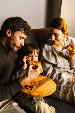 Mutlu aile Noel 'i kutlar, film izler ve yılbaşı ağacının yanında patlamış mısır ve pizza yer. Dikey fotoğraf