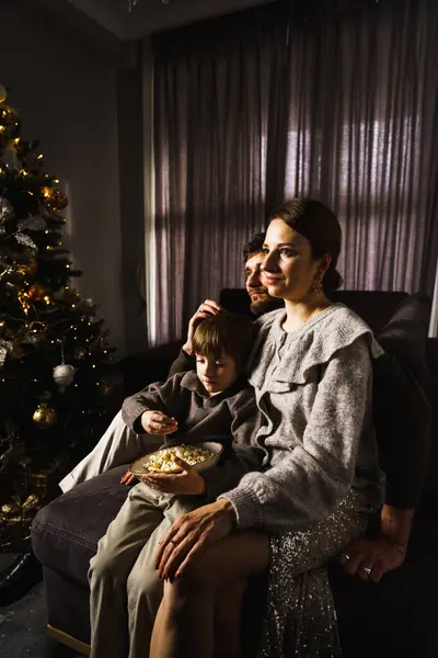 Happy family  celebrate Christmas, watch movies and eat popcorn and pizza near the New Year tree. Vertical photo