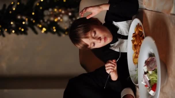 メリークリスマス 幸せな家族が家で夕食を食べています お祝いの休日と木の近くのトータルネス クリスマステーブルで父 母と息子 クリスマスと新年のコンセプト 垂直ビデオ — ストック動画