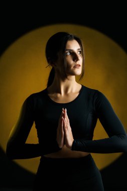 Atletik kadın stüdyoda yoga yapıyor ve arka plandaki ışık aydınlatmalarına karşı poz veriyor. Yoga ve meditasyon konsepti