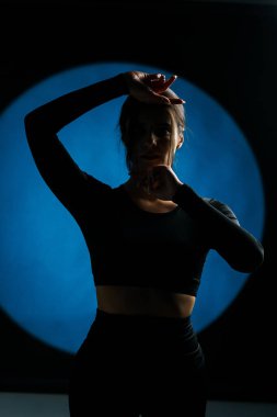 Atletik kadın stüdyoda yoga yapıyor ve arka plandaki ışık aydınlatmalarına karşı poz veriyor. Yoga ve meditasyon konsepti