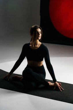 Atletik kadın stüdyoda yoga yapıyor ve arka plandaki ışık aydınlatmalarına karşı poz veriyor. Yoga ve meditasyon konsepti