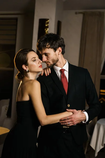 A stylish man and woman in evening wear, a suit and a dress, posing against the backdrop of a luxurious hotel. Casino concept
