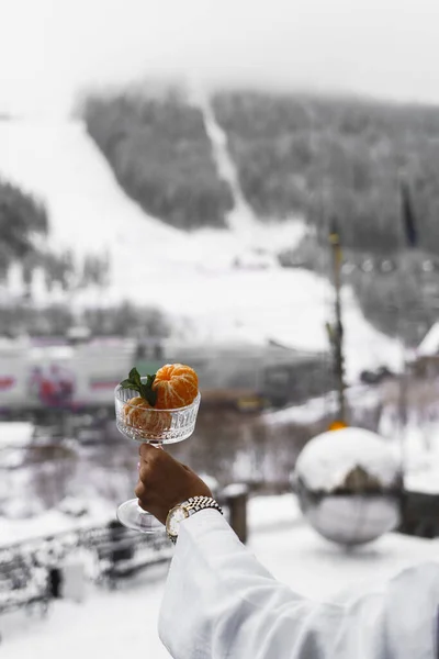 New Year\'s breakfast on the hotel balcony in the mountains. Coffee with croissant, juice and tangerines against the backdrop of snow-capped mountains. Concept of winter holidays