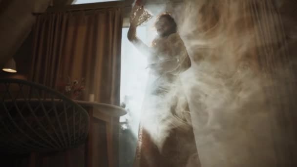 一个穿着婚纱的时装模特站在一个有浓烟和阳光的房间里 时尚婚纱照的概念 — 图库视频影像