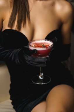Siyah elbiseli, kırmızı dudaklı seksi kadın kokteyl tutuyor. Gece hayatı konsepti.