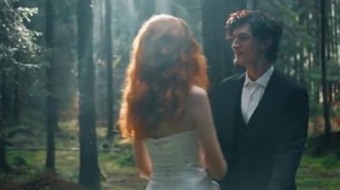 Kızıl saçlı bir gelin, damatla çam ormanında poz veriyor. Peri masalı çifti. Düğün konsepti