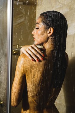 Genç ve güzel bir kadın duş alıyor. Vücut bakımı kavramı