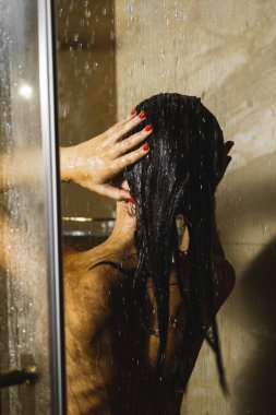 Genç ve güzel bir kadın duş alıyor. Vücut bakımı kavramı