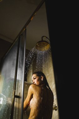 Genç ve güzel bir kadın duş alıyor. Vücut bakımı kavramı