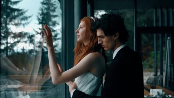 童话般的新婚夫妇在一间有着全景窗户和山景的时髦房子里摆姿势 红头发的新娘和新郎摆姿势 结婚的概念 — 图库视频影像