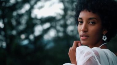 A dark-skinned bride in a white dress poses in the mountains on the terrace. Wedding concept. Portrait of a dark-skinned bride 4k