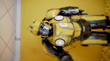 Stüdyoda poz veren bir Bumblebee transformatörü. Bumblebee kostümlü bir adam dans eder ve eğlenir. Bumblebee film konsepti. Dikey video