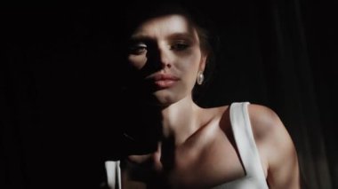 Beyaz eldivenli şık bir kadın model, güneş gören bir pencerenin yanında poz veriyor. Gölgede bir mankenin portresi. Moda çekimi konsepti 4k