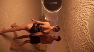 Genç bir adam ve bir kadın tuz odasında dinleniyor. Sağlık tatili konsepti. Dikey video