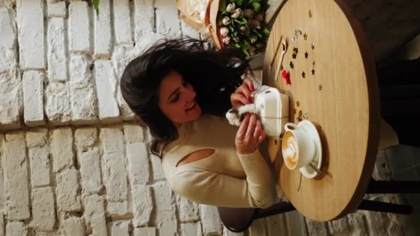 ハッピー女性 コーヒーを飲んで チューリップと弁当ケーキの花束でコーヒーショップで誕生日を祝う 誕生日コンセプト 弁当のケーキギフト 垂直ビデオ — ストック動画