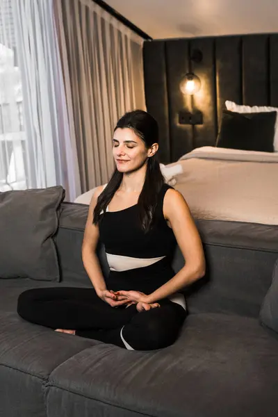 Athletic woman doing meditation at home in a cozy apartment. Yoga and meditation concept. Home fitness
