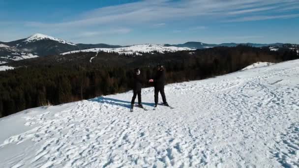 男性と女性はスキーをして山の美しい景色を楽しんでいます 山での冬の休日のコンセプト 4Kドローン映像 — ストック動画