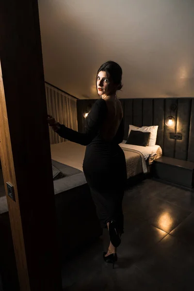 Stock image Elegant woman in a black dress posing in an apartment. Fashion shooting concept