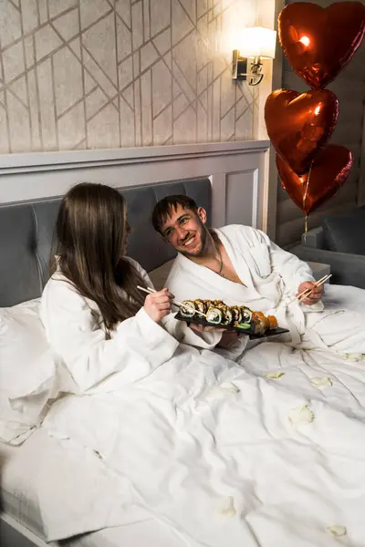 Couple in love eating sushi in bed.Valentine\'s day concept