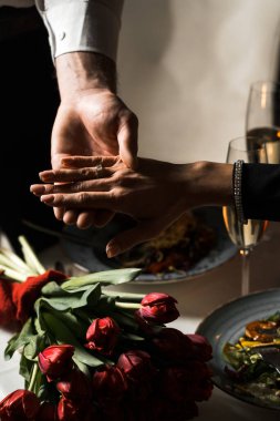 Adam bir restoranda sevgilisine nişan yüzüğüyle evlenme teklif ediyor. Sevgilisinin eline nişan yüzüğü takan bir adamın yakın çekimi. Evlilik teklifi konsepti