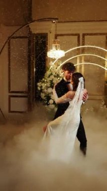 Gelin ve damat düşen karda ilk dansı yaparlar. Düğün günü. İlk düğün dansının konsepti. Dikey video. 4k