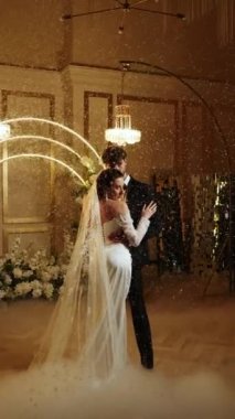 Gelin ve damat düşen karda ilk dansı yaparlar. Düğün günü. İlk düğün dansının konsepti. Dikey video. 4k