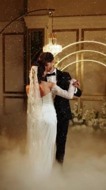 Gelin ve damat düşen karda ilk dansı yaparlar. Düğün günü. İlk düğün dansının konsepti. Dikey video. 4k