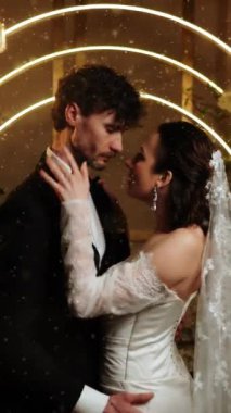 Gelin ve damat düşen karda ilk dansı yaparlar. Düğün günü. İlk düğün dansının konsepti. Dikey video. 4k