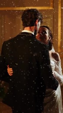 Gelin ve damat düşen karda ilk dansı yaparlar. Düğün günü. İlk düğün dansının konsepti. Dikey video. 4k