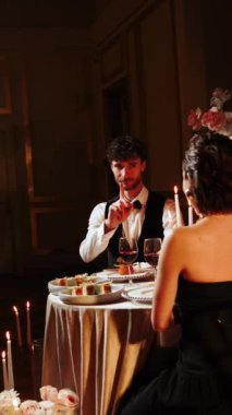 Birbirine aşık bir çiftin romantik yemeği. Bir adam ve bir kadın bir restoranda birlikte akşam yemeği yiyorlar. Adam kıza evlenme teklif etmiş. Kız da evet demiş. Evlilik teklifi konsepti. Dikey video