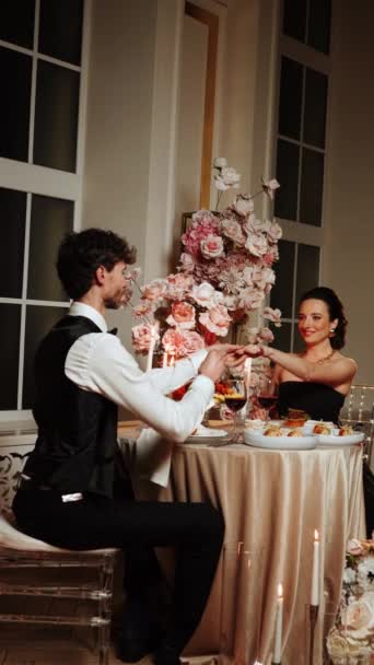 一对恋人恋爱中的浪漫晚餐 一个男人和一个女人在一家餐馆里一起吃饭 男人向女孩求婚 她说是的 求婚的概念 垂直录像 — 图库视频影像