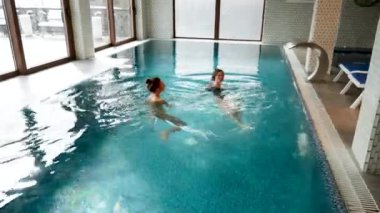 İki seksi kadın havuzda yüzüyor. Kadınlar spa 'da rahatlıyor. Otelde rahatlama konsepti.