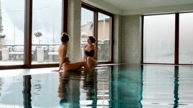 İki seksi kadın havuzda yüzüyor. Kadınlar spa 'da rahatlıyor. Otelde rahatlama konsepti.