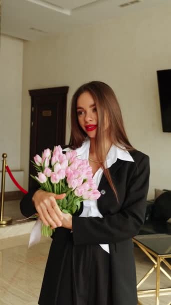 一个穿着黑色西服的漂亮女人拿着新鲜的郁金香花 郁金香花在一个女人手里 — 图库视频影像