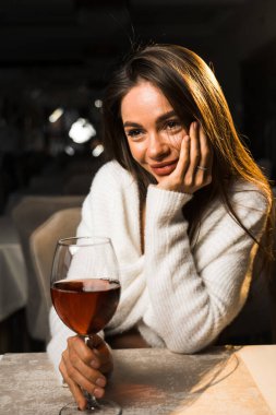 Bir bardak şarap tutan genç bir kadın. Restoranda şarap içen bir kadın. Kırmızı şarap konsepti.
