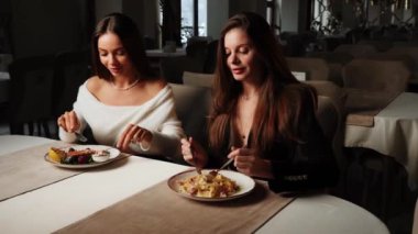 İki genç kadın bir restoranda yemek yiyor. İki arkadaşla buluşmak ve birlikte yemek yemek. Restoran konsepti