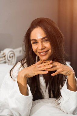 Genç ve güzel bir kadın aydınlık otel odasında uyanıyor. Mutlu bir kadının sabahı. Otel tatil konsepti.