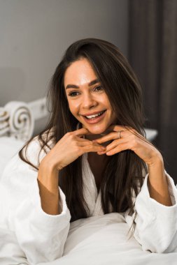 Genç ve güzel bir kadın aydınlık otel odasında uyanıyor. Mutlu bir kadının sabahı. Otel tatil konsepti.