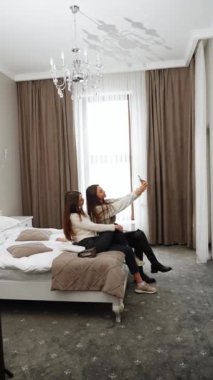 İki genç kadın tatile çıkıyor. Bir kadın otele yerleşiyor, gülüyor ve selfie çekiyor. Dikey video