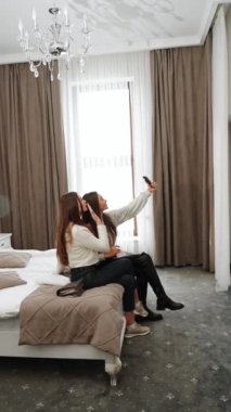 İki genç kadın tatile çıkıyor. Bir kadın otele yerleşiyor, gülüyor ve selfie çekiyor. Dikey video