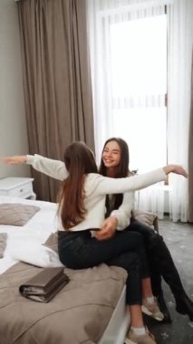 İki genç kadın tatile çıkıyor. Bir kadın otele yerleşiyor, gülüyor ve selfie çekiyor. Dikey video